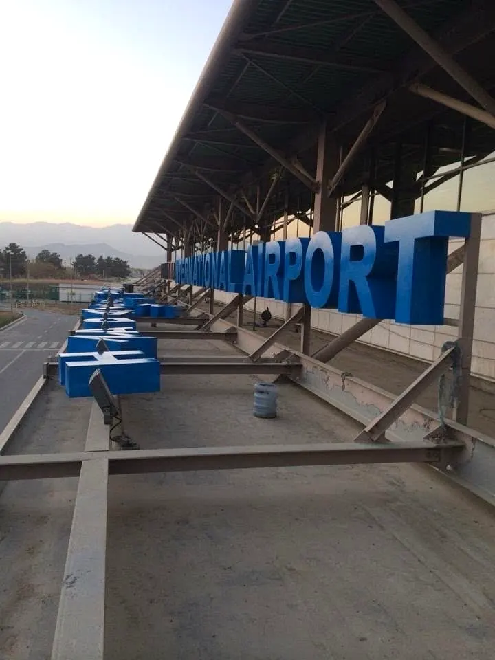 Site photograph from the terminal roof showing the blue airport letters on their steel support frame.