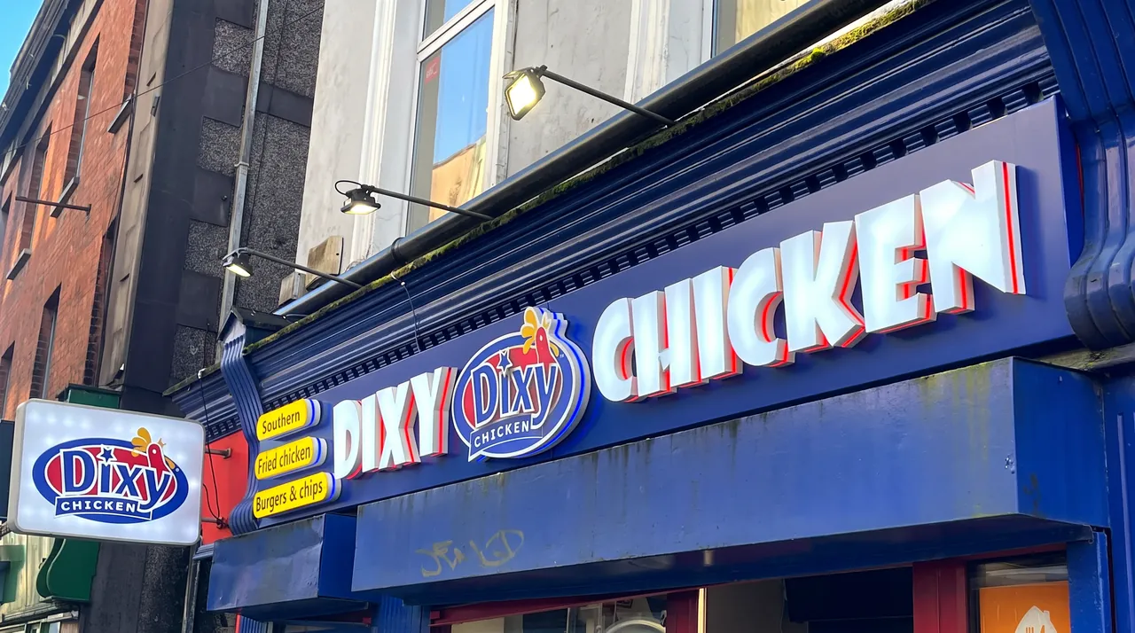 Dixy Chicken shopfront in Cork: white 3D built-up letters with red returns on a navy fascia, the Dixy logo, and a matching projecting light box.