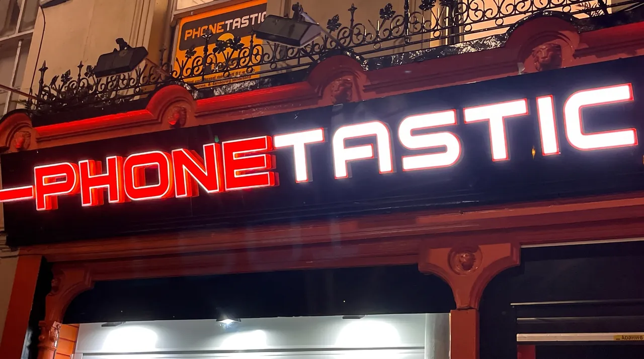 Phonetastic fascia in Cork at night: red and white illuminated 3D letters on a black fascia.