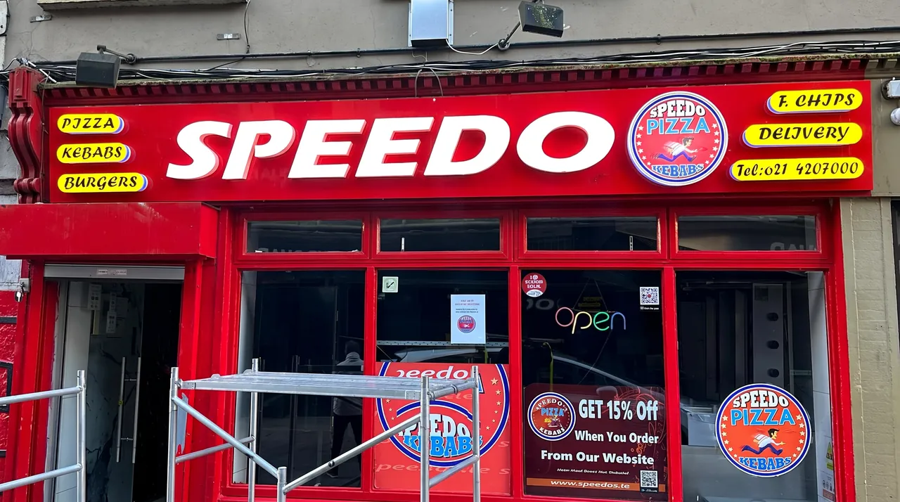 Speedo pizza and kebab shopfront in Cork: red fascia with large white SPEEDO letters, logo and yellow menu panels.